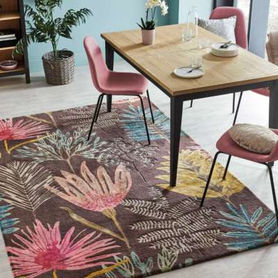 Dining area with a floral rug, wooden table, and pink chairs.